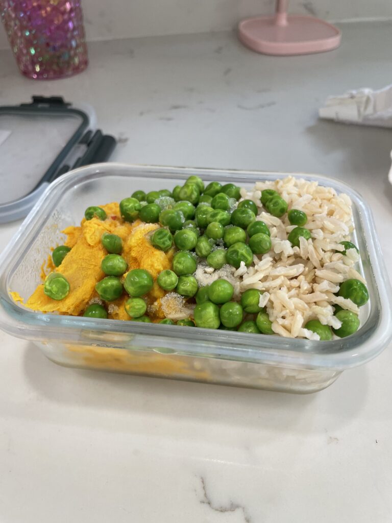 glass freezer container of curry cauliflower with peas