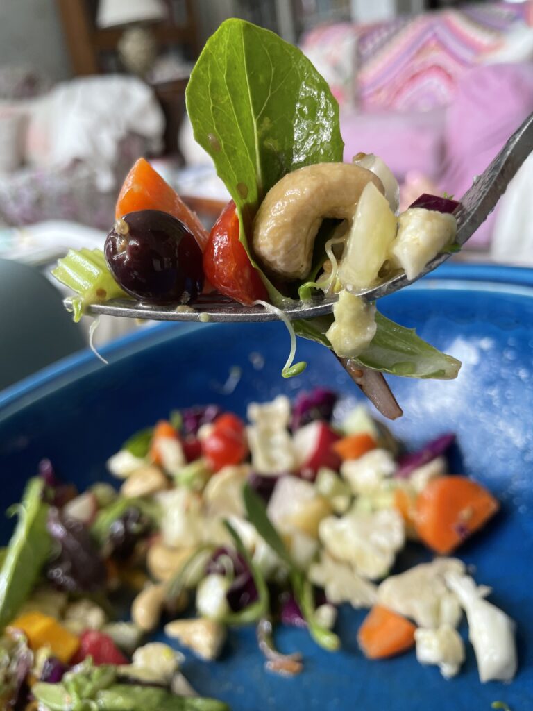 Fork full of chopped salad in blue bowl