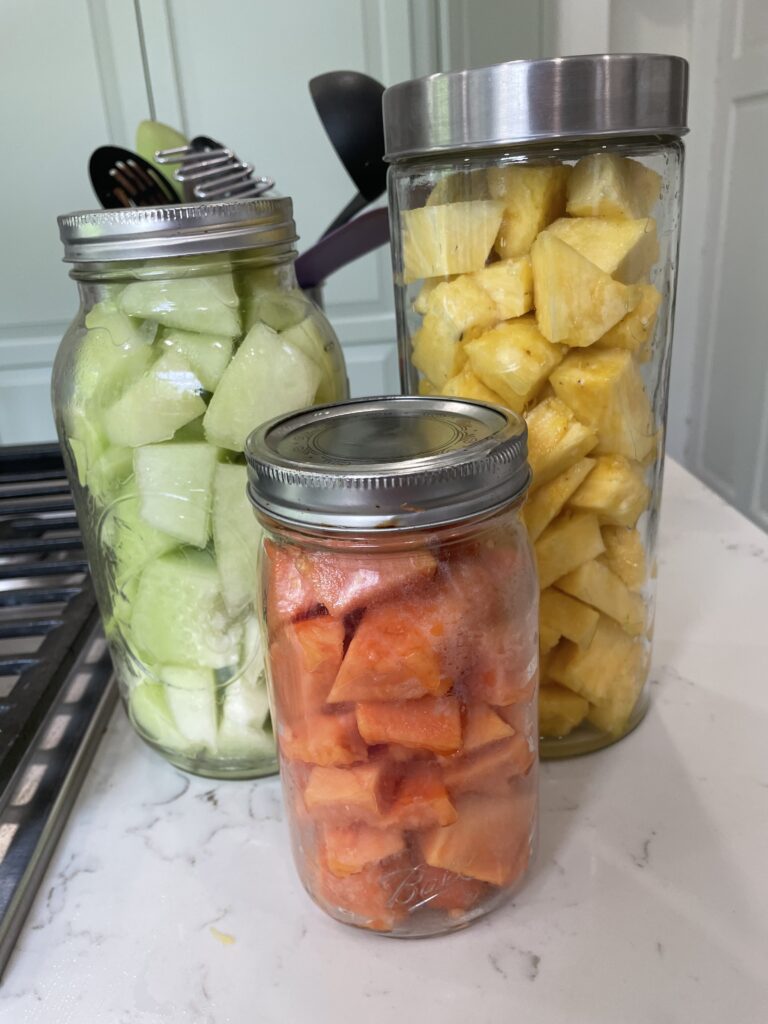 3 jars of prepped fruit. honeydew melon, papaya and pineapple